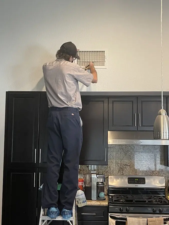 Technician inspecting an air vent during HVAC service in Dickinson